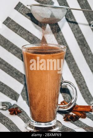 Traditionelle Winter-Eierlikör in Glas Becher mit Milch, Zimt und Anis Sterne mit Schlagsahne auf einem grauen Tuch bedeckt, Stockfoto