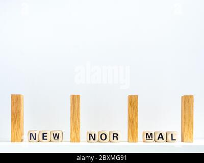 Konzept der sozialen Distanzierung. Reihe von hölzernen Dominosteine mit Abstand Raum und New Normal, Wörter auf hölzernen Alphabet Würfel auf weißem Hintergrund mit Kopie-Raum Stockfoto