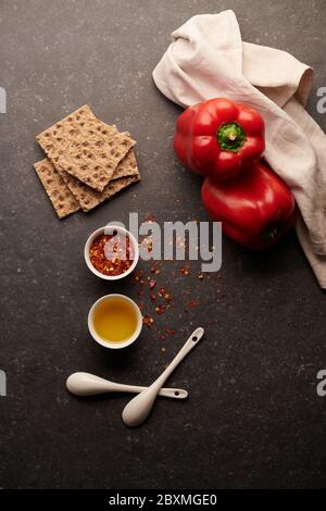 Olivenöl mit Chilischoten in Stücken, Olivenöl, Paprika und Cracker, auf dunklem Hintergrund Stockfoto