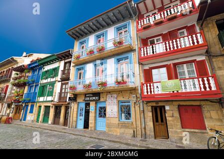 Bunte Stadthäuser mit Balkonen und roten und blauen Fenstern säumen eine mittelalterliche Straße im Stadtzentrum von Hondarribia Stockfoto