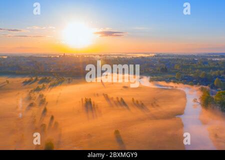 Nebliger Sonnenaufgang über der Landschaft, Nebel in den Tiefebenen über den überfluteten Sümpfen entlang des Flusses. Landshat Luftaufnahme. Stockfoto