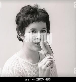Eis in den 1960er Jahren. Ein Mädchen isst ein mit Schokolade überzogenes Vanilleeis. Schweden 1962. Kristoffersson CU5-12 Stockfoto