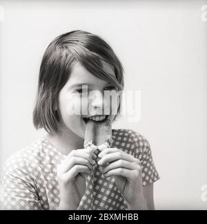 Eis in den 1960er Jahren. Ein Mädchen isst ein mit Schokolade überzogenes Vanilleeis. Schweden 1962. Kristoffersson CU5-4 Stockfoto