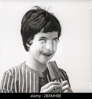 Eis in den 1960er Jahren. Ein Mädchen isst ein mit Schokolade überzogenes Vanilleeis. Schweden 1962. Kristoffersson CU5-7 Stockfoto