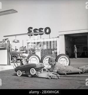 Tankstelle der 1950er Jahre. Ein Junge in seinem Tretauto lässt es an einer Esso-Tankstelle warten. Ein Servicemann hat das kleine Auto angehoben und bedient es. Das Pedalauto wird in Italien von der Firma Giordani hergestellt. Schweden 1958. Kristoffersson Ref. DC100-11 Stockfoto