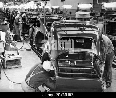Automobilbau in den 1950er Jahren. Die Saab Autofabrik in Trollhättan Schweden mit ihrer Produktionslinie. Arbeiter an einer Montagelinie fügen Teile hinzu, während die Karosserien von Arbeitsplatz zu Arbeitsplatz wechseln, bis die Endmontage hergestellt ist. Das Modell ist Saab 93. Ein Dreizylinder-Zweitaktmotor mit 33 ps. Stockfoto