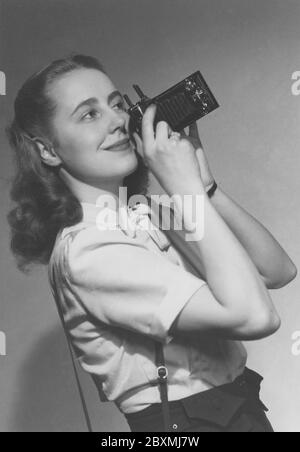 Amateurfotograf in den 1940er Jahren. Eine junge Frau fotografiert an einem Sommertag. Das Kameramodell ist praktisch. Wenn Sie es nicht verwenden, werden die Linse und der Balg in das Kameragehäuse gefaltet. Um Bilder aufzunehmen, haben Sie es geöffnet und waren bereit zu gehen. Die Kamera produzierte analogen Film. Margareta von Törne ist beim Fotografieren abgebildet und die Fotografie wurde ursprünglich auf dem Cover eines Buches mit dem Titel Handbuch für den Amateurfotografen 1948 verwendet. Stockfoto