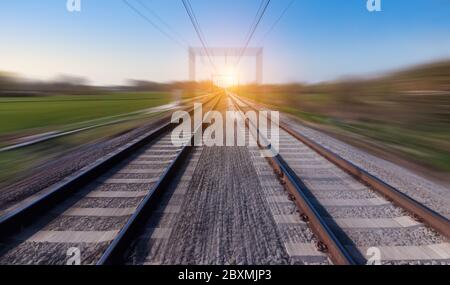 Bahnstrecke in Bewegung. Verwischte Schienenlandschaft bei Sonnenuntergang. Stockfoto