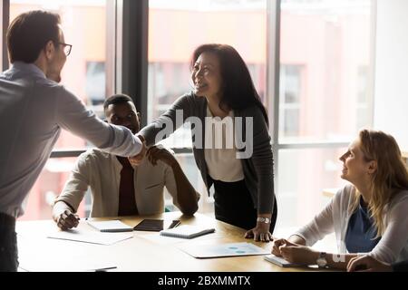 Mittelalter asiatischer Geschäftsfrau schütteln die Hände mit europäischen Millennial Client Stockfoto