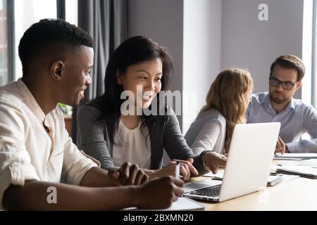 Multiethnische jüngere ältere Partner arbeiten an Aufgabe mit Laptop zusammen Stockfoto