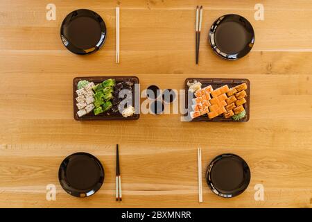 Nahaufnahme einer Mischung aus Sushi-Brötchen auf einem Tisch zu Hause. Warten Freunde, Sushi Rollen zusammen mit Bambusstäbchen essen. Stockfoto