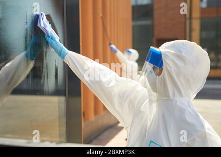 Seitenansicht Porträt von zwei Arbeitern tragen Schutzanzüge Reinigung Gebäude im Freien während der Desinfektion, Kopierraum Stockfoto