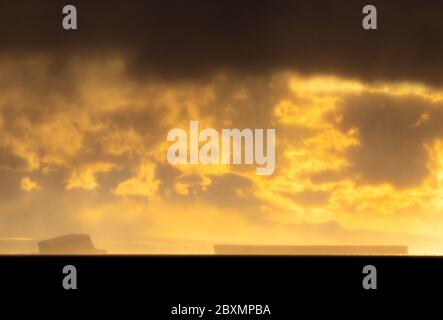 Eisberge in Tabellenform am Horizont bei Sonnenuntergang in der Antarktis. Stockfoto