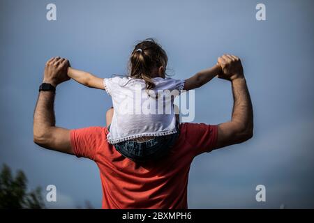 Familienwerte. Vater und Tochter treffen den Sonnenuntergang. Er wird das Mädchen auf seine Schultern legen und ihre Hände halten. Konzept Vatertag. Stockfoto