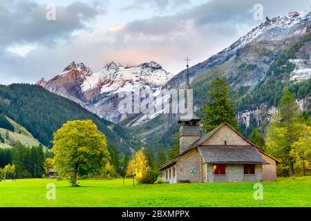 Sonnenuntergang Panorama von Kandersteg alte Kirche, Kanton Bern, Schweiz, Europa, Bäume im Herbst und den Sonnenuntergang Berge Panorama Stockfoto