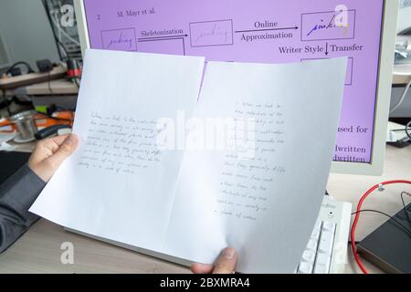 Erlangen, Deutschland. Juni 2020. Ein Forscher der Universität Erlangen-Nürnberg zeigt in der rechten Hand ein mit der Software generiertes Beispiel und in der linken Hand ein Beispiel einer echten Handschrift. Quelle: Daniel Karmann/dpa/Alamy Live News Stockfoto