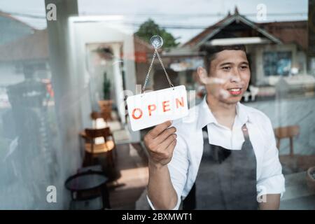 Der Kellner hält das Schild, wenn er morgens den Coffee Shop öffnet Stockfoto