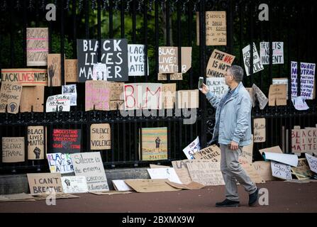 Ein Mann fotografiert Plakate und Plakate, die am Geländer des Palace of Holyroodhouse nach der Protestkundgebung von Black Lives Matter am Sonntag im Holyrood Park, Edinburgh, aufgehängt sind. In Erinnerung an George Floyd, der am 25. Mai in Polizeigewahrsam in der US-Stadt Minneapolis getötet wurde. Stockfoto