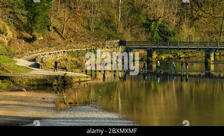 Menschen, die auf Stepping-Stones über das Wasser des Flusses Wharfe (über Fußgängerbrücke) in der Sonne - landschaftlich schöne Bolton Abbey Anwesen, Yorkshire Dales, England, Großbritannien. Stockfoto