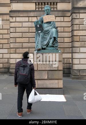 Ein Plakat hängt an der Statue des Philosophen David Hume aus dem 18. Jahrhundert auf der Royal Mile, Edinburgh, nach der Protestkundgebung von Black Lives Matter am 7. Juni 2020 im Holyrood Park, Edinburgh, In Erinnerung an George Floyd, der am 25. Mai in Polizeigewahrsam in der US-Stadt Minneapolis getötet wurde. Stockfoto