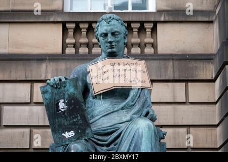 Ein Plakat hängt an der Statue des Philosophen David Hume aus dem 18. Jahrhundert auf der Royal Mile, Edinburgh, nach der Protestkundgebung von Black Lives Matter am 7. Juni 2020 im Holyrood Park, Edinburgh, In Erinnerung an George Floyd, der am 25. Mai in Polizeigewahrsam in der US-Stadt Minneapolis getötet wurde. Stockfoto