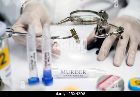 Experten der Polizei untersucht eine bullet Gap im wissenschaftlichen Labor mit Lupe Stockfoto