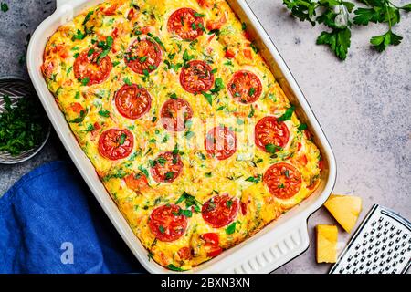 Traditionelle Eierfrittata mit Tomaten und Käse in der Ofenform, Draufsicht. Omelette mit Gemüse und Käse gebacken. Stockfoto