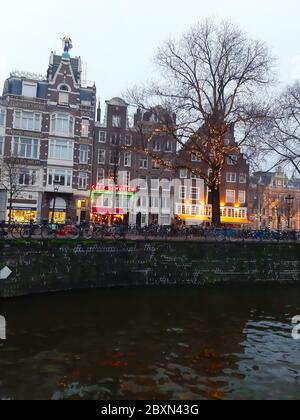 Typische Backsteingebäude und Geschäfte entlang des Wassers der Kanäle des Flusses in amsterdam in den niederlanden Stockfoto