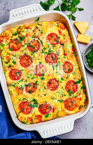 Traditionelle Eierfrittata mit Tomaten und Käse in der Ofenform, Draufsicht. Omelette mit Gemüse und Käse gebacken. Stockfoto