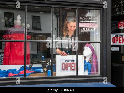 Carrigaline, Cork, Irland. Juni 2020. Kasia Nita von Stich & Design in Carrigaline, Co. Cork, die das "Open"-Schild in ihrem Schaufenster zu Beginn der zweiten Phase der Roadmap der Regierung für die Wiedereröffnung der Gesellschaft nach der Covid-19-Pandemie platziert. - Credit; David Creedon / Alamy Live News Stockfoto