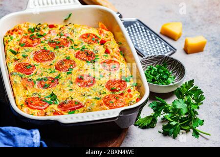 Traditionelle Eierfrittata mit Tomaten und Käse in der Ofenform, Draufsicht. Omelette mit Gemüse und Käse gebacken. Stockfoto