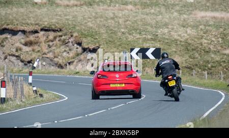 Motorradfahrer überholen ein Auto an einer gefährlichen Ecke auf der B6255 Ingleton Hawes Straße, wo es regelmäßige Unfälle. North Yorkshire, Großbritannien. Stockfoto