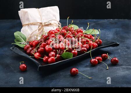 Frische süße Kirsche dunklen Hintergrund, umweltfreundliche Verpackung. Nahaufnahme Foto für Lebensmittelkatalog speichern. Stockfoto