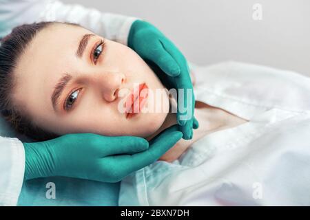 Hände einer Kosmetikerin um das Gesicht des Patienten, kümmern sich um das Aussehen, Schönheit, Anti-Aging-Verfahren. Stockfoto