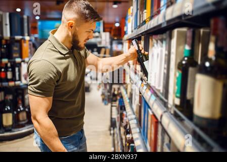 Mann, der Alkoholprodukte im Lebensmittelgeschäft auswählt Stockfoto