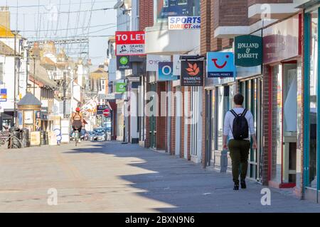 Worthing, Sussex, Großbritannien; 29. Mai 2020; Fußgängerzone, die fast leer ist, außer einem Mann, der läuft und einer Frau, die ein Fahrrad reitet, beide von hinten gesehen Stockfoto