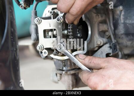 Foto der Hand hält den Schlüssel, Reparatur des Motorrads in der Garage, Nahaufnahme Stockfoto