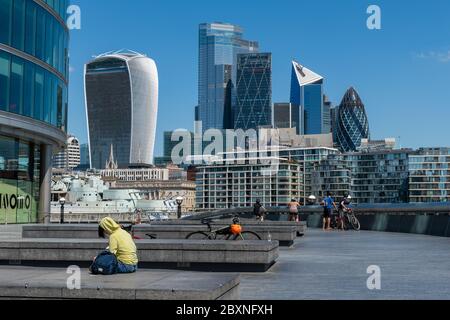 Besucher der South Bank genießen einen schönen warmen Tag an der Themse mit Blick auf die City of London. England.Vereinigtes Königreich. Stockfoto