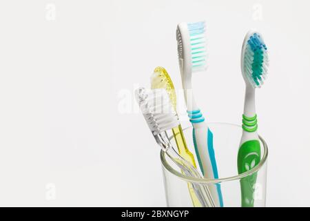 Set von bunten Zahnbürsten in Glas auf weißem Hintergrund. Stockfoto