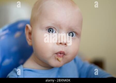 Porträt eines lustigen blauäugigen Kindes mit Apfelmus Stockfoto