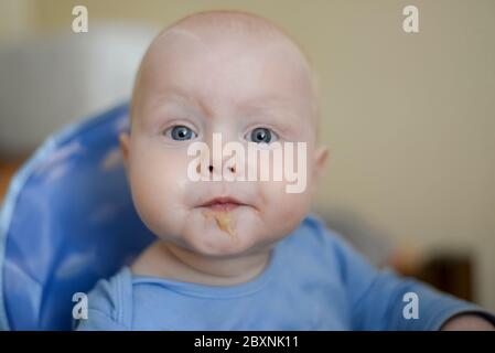 Porträt eines lustigen blauäugigen Kindes mit Apfelmus Stockfoto