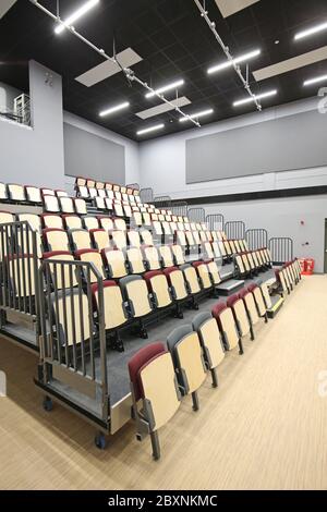 Ausziehbare Bleacher-Sitzmöbel in einer neu erbauten Schulhalle im Süden Londons, Großbritannien. Zeigt das System vollständig ausgefahren und bietet 9 Reihen gestufter Sitzplätze. Stockfoto