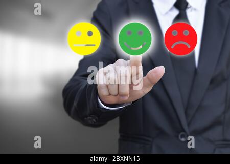 Geschäftsmann drücken Smiley Gesicht Symbol auf virtuellen Bildschirm. Konzept der Zufriedenheitsbewertung und Feedback. Stockfoto