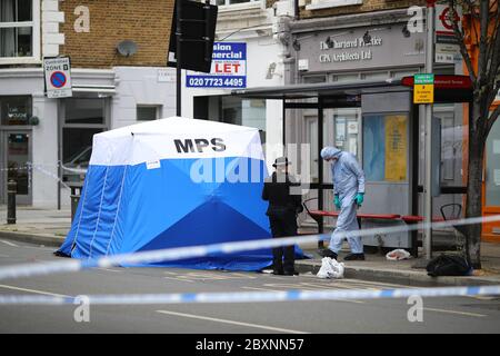 Ein Gerichtsbeamter in einem Polizeizelt am Tatort in Askew Road, Shepherd's Bush, West London, als eine Morduntersuchung eingeleitet wurde, nachdem ein Mann erschossen wurde. Das Opfer, das vermutlich um die 20 Jahre war, wurde in den frühen Morgenstunden des Montags mit Schusswunden gefunden. Stockfoto