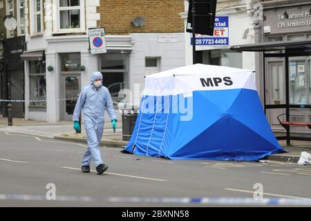 Ein Gerichtsbeamter in einem Polizeizelt am Tatort in Askew Road, Shepherd's Bush, West London, als eine Morduntersuchung eingeleitet wurde, nachdem ein Mann erschossen wurde. Das Opfer, das vermutlich um die 20 Jahre war, wurde in den frühen Morgenstunden des Montags mit Schusswunden gefunden. Stockfoto