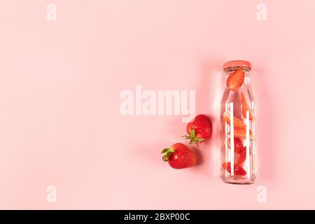 Draufsicht Zusammensetzung der hausgemachten Detox Limonade mit Bio-köstlichen Erdbeerbeeren in Glasflasche. Sommer Komposition, minimalistischer Stil Stockfoto