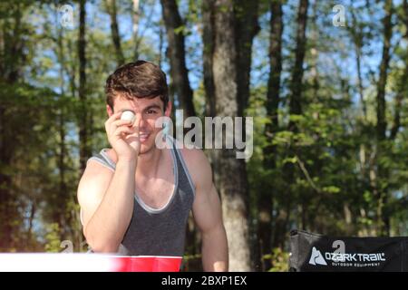 Junger Mann schießt auf Bierpong in einer Campingszene. Stockfoto