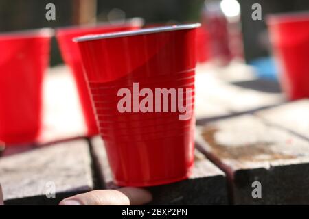 Rote Party Cups Themen Hintergrundvorlage. Weißer Hintergrund. Alkoholbehälter auf der Seite. Menschen tanzen Hände hoch in der Luft. Leerer leerer Kopierplatz Stockfoto