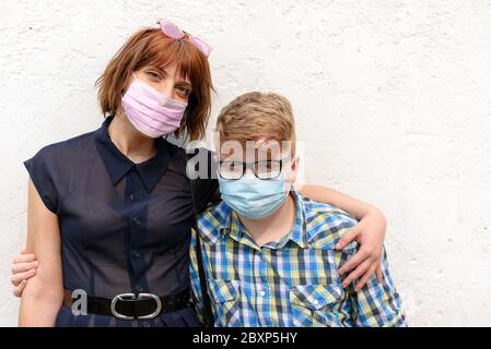 Schwester trägt trendige Brille und kleiner Bruder mit Brille posiert zusammen Blick auf die Kamera.Junge rothaarige Frau und Junge trägt eine chirurgische Stockfoto