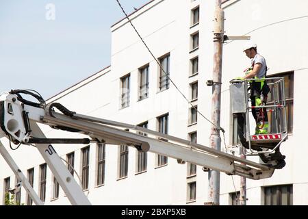 Belgrad, Serbien - 24. April 2020: Bauarbeiter im Krankorb, Kirschpflücker, Installation von Metallhalter auf Straßenlichtmast Stockfoto